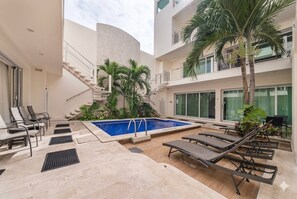 Un espace piscine avec des chaises longues, un escalier et un palmier.