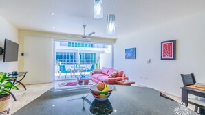 Een moderne woonkamer met een salontafel van zwart marmer, een rode bank en een eethoek met een zwarte tafel en stoelen.