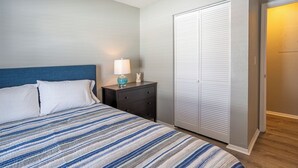 Un dormitorio con cama, mesita de noche, lámpara y armario.
