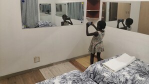 A room with a bed, a mirror, and a shelf. - Family room (Khomasdal)