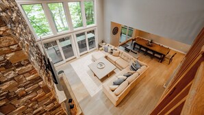 Ein großzügiger Wohnbereich mit einem großen Fenster, einem Sofa, einem Couchtisch und einem Esstisch.