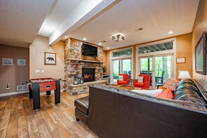 A cozy living room with a stone fireplace, a foosball table, and comfortable seating.