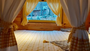 Una habitación acogedora con una cama, cortinas de cuadros y una ventana que da a una zona boscosa.