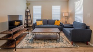 A living room with a sofa, coffee table, TV, and a ladder.