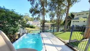 A hot tub on a wooden deck with a view of a swimming pool and a fenced yard. - Holiday on the Waterfront in Pittwater -Beach, Swim, Kayak, Boat, Fish and More! (Newport)