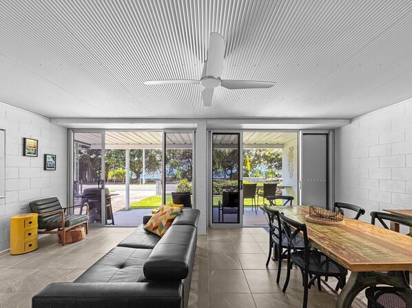 A modern interior with a sofa, dining table, chairs, and a ceiling fan.
