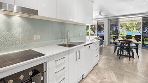 Une cuisine moderne avec des meubles blancs, une hotte de cuisinière en acier inoxydable et un lave-vaisselle intégré.