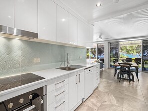 A modern kitchen with white cabinetry, a stainless steel range hood, and a built-in dishwasher.
