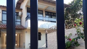 Une cour intérieure avec un bâtiment doté d’un toit en tuiles, d’un balcon et d’un mur en briques sur lequel grimpe une plante.