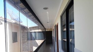 Un couloir doté de grandes fenêtres, d’un sol carrelé et d’un plafond équipé d’un éclairage encastré.