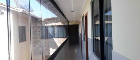 A corridor with large windows, a tiled floor, and a ceiling with recessed lighting.