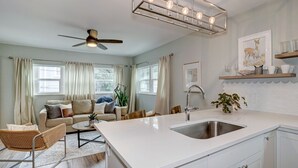 Une cuisine moderne dotée d’un grand îlot central, de meubles blancs et d’un ventilateur de plafond.