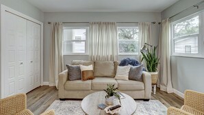 Un salon avec un canapé beige, une table basse ronde, des fauteuils en osier et une plante en pot.