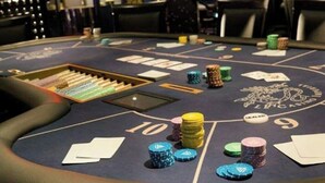 A blackjack table with chips, cards, and a dealer's stand in a dimly lit room. - Impérial Palace (Annecy)