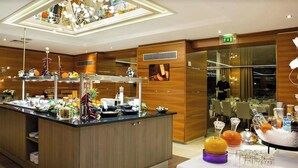 A buffet area with a variety of food items and a dining section with tables set for guests. - Impérial Palace (Annecy)