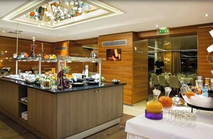 Buffet-alue, jossa on tarjolla monipuolinen valikoima ruokia, sekä ruokailutila, jossa on katetut pöydät vieraille.