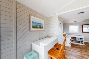 Cozy retreat with a high ceiling, bench, and wooden chair, perfect for reading and relaxation.