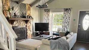 A spacious living area with a sofa, TV, fireplace, and a staircase.
