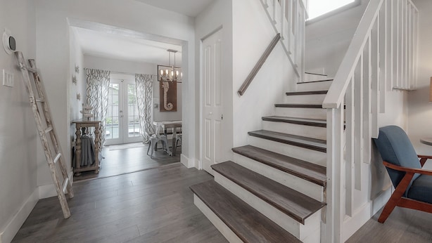 A staircase with wooden steps and white railings leading to an upper floor.