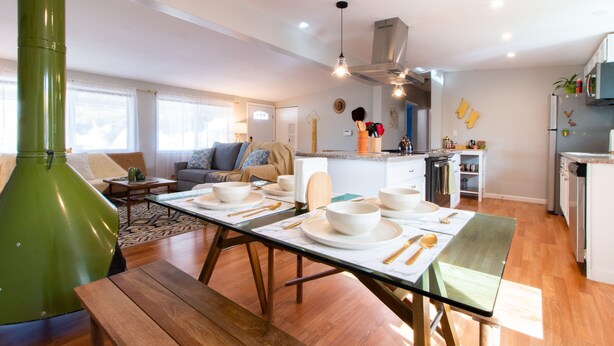 Une cuisine moderne avec un coin repas, un plancher en bois et un élément décoratif de couleur verte.