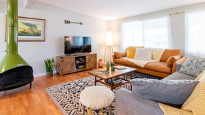 Un salon avec un canapé, une table basse et un téléviseur posé sur un meuble en bois.