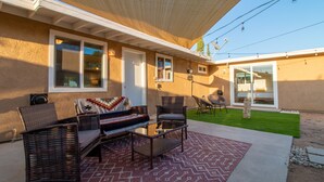 Un espace patio aménagé avec du mobilier d’extérieur, un coin salon abrité et une vue sur le jardin arrière.
