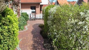 A residential area with a brick house, a paved pathway, and a flag.