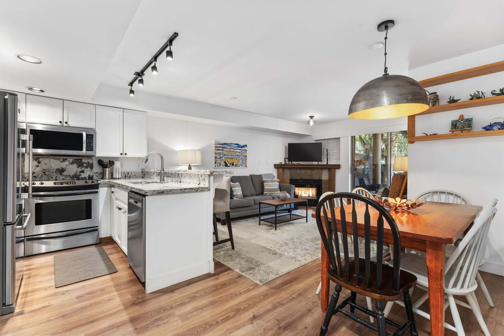 A modern kitchen with built-in appliances, a dining area with a wooden table and chairs, and a fireplace.