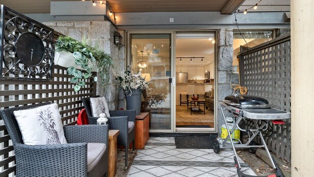 Un patio al aire libre con mobiliario de mimbre, un reloj y una parrilla.