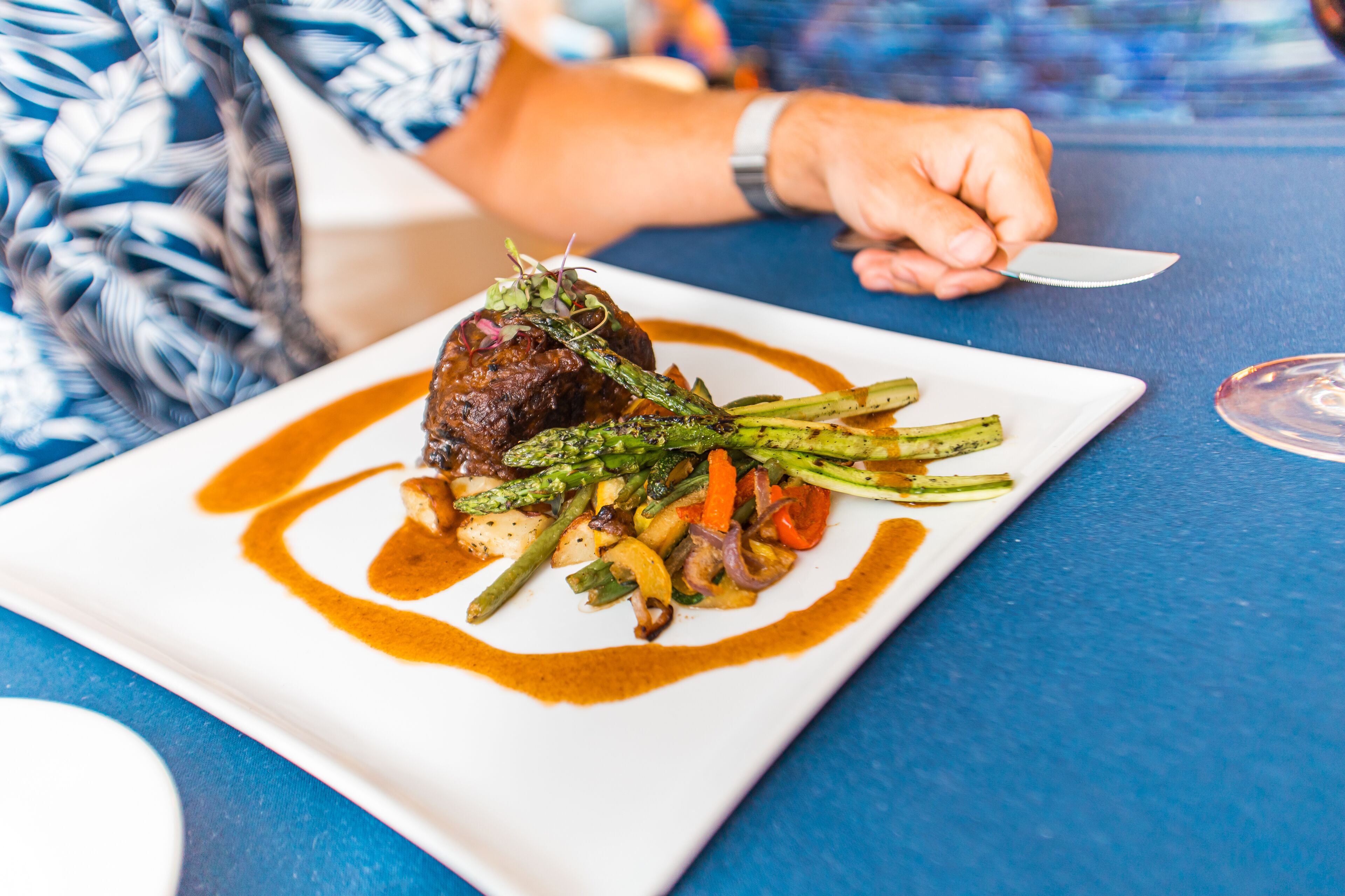 A beautifully plated gourmet meal awaits you at the property's restaurant, featuring succulent meat, fresh grilled vegetables, and an artful sauce presentation.