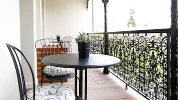 A balcony with a round table, two chairs, a potted plant, and a decorative railing.