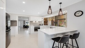 Una cocina moderna con armarios blancos, una isla central e iluminación colgante.