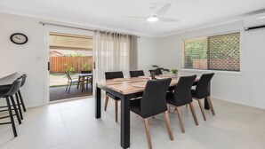 Un comedor con una mesa y sillas, un ventilador de techo y vistas al patio trasero a través de una puerta.