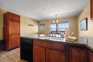 A kitchen with a dishwasher, a sink with a faucet, and a window with a view. - Mountain Brook Condo 150 - Ski in ski out condo at Saddleback (Sandy River Plantation)