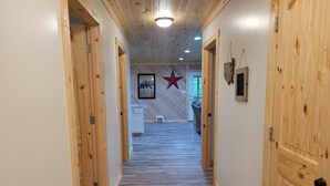 Un pasillo revestido de madera con un adorno de estrella en la pared, un taburete pequeño y un cuadro enmarcado.