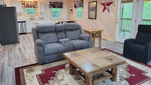 Una sala de estar acogedora con un sofá gris, una mesa de centro de madera y un tapete rojo y beige estampado.