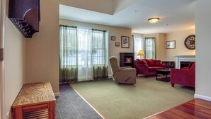 A spacious living room with a fireplace, red sofas, and a large window with curtains.