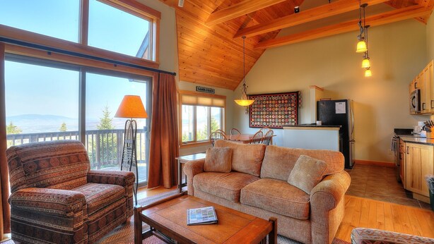 A cozy living room with a sofa, armchair, and coffee table, a dining area with a table and chairs, and a kitchen with a refrigerator and stove.