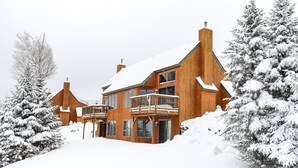 A large wooden house with multiple balconies and a snow-covered landscape.