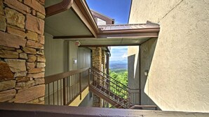 Escadaria que leva a uma varanda com um muro de pedra e vista para as montanhas.