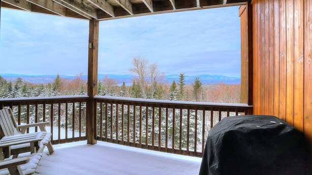En träveranda med utsikt över ett snötäckt landskap och berg.