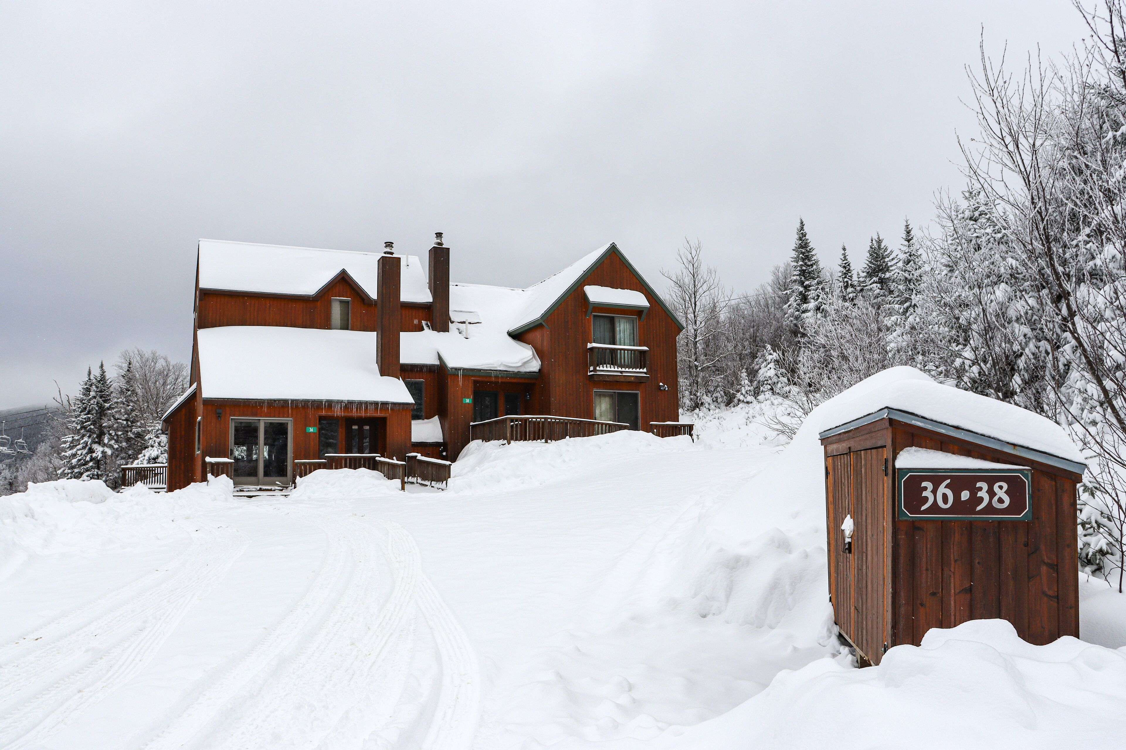 Une grande maison en bois, dont le toit est recouvert de neige, et sur laquelle on peut lire l’inscription « 36-38 ».