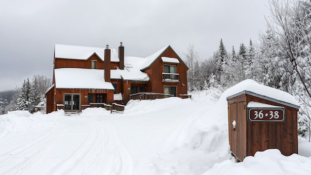 A large wooden house with a snow-covered roof and a sign reading "36-38". - Rock Pond 36 | Ski-In/Ski-Out Saddleback Mountain Condo (Rangeley)