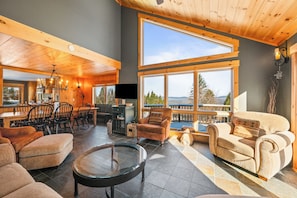 A spacious living area with a large window, a fireplace, and a dining area with wooden furniture.