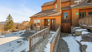 A wooden lodge with a covered porch and a stone staircase leading to the entrance. - Rock Pond 36 | Ski-In/Ski-Out Saddleback Mountain Condo (Rangeley)