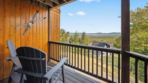 Una terraza de madera con vistas a un valle y montañas.