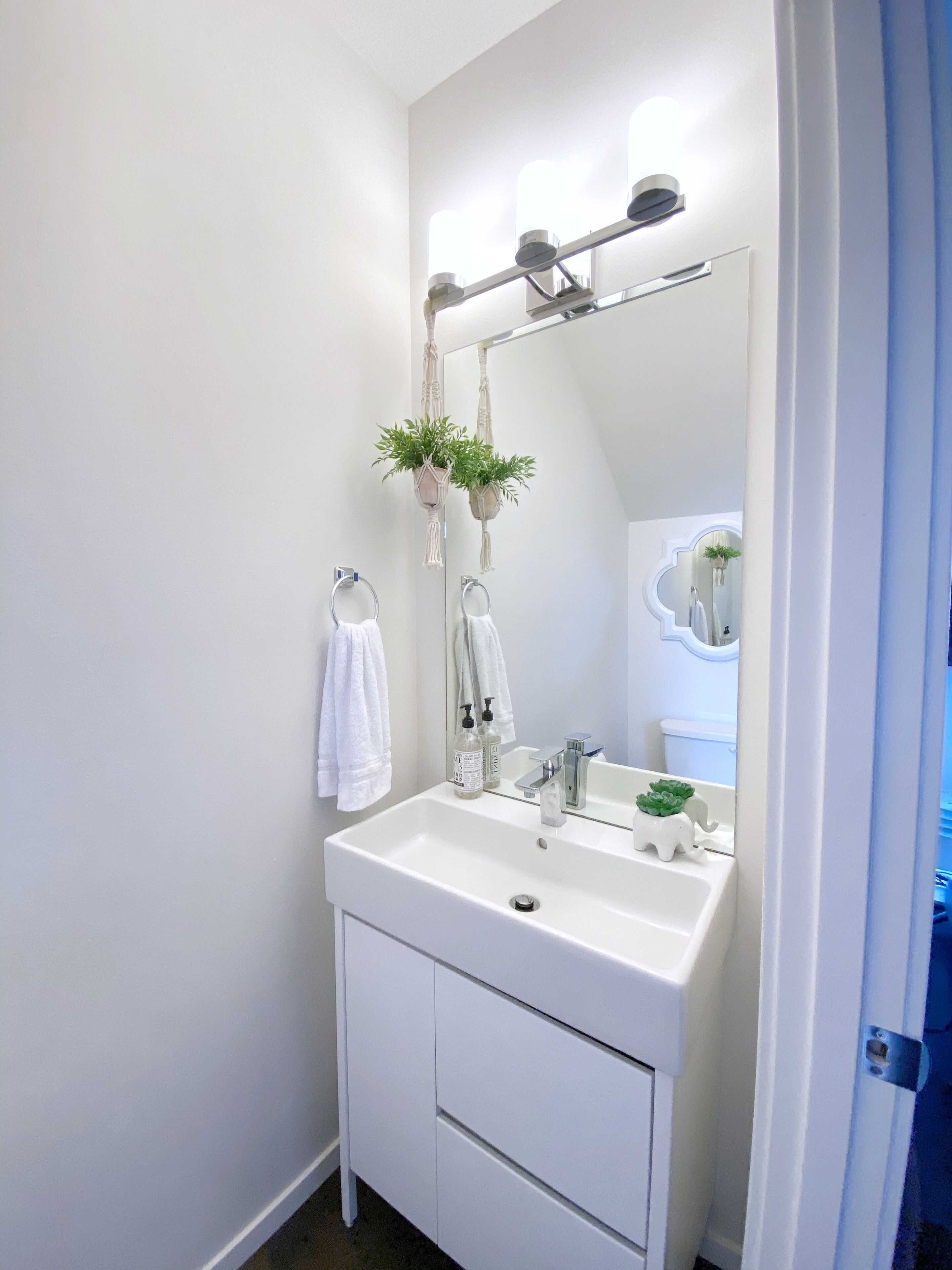 A bathroom with a white sink, a mirror, and a towel rack.