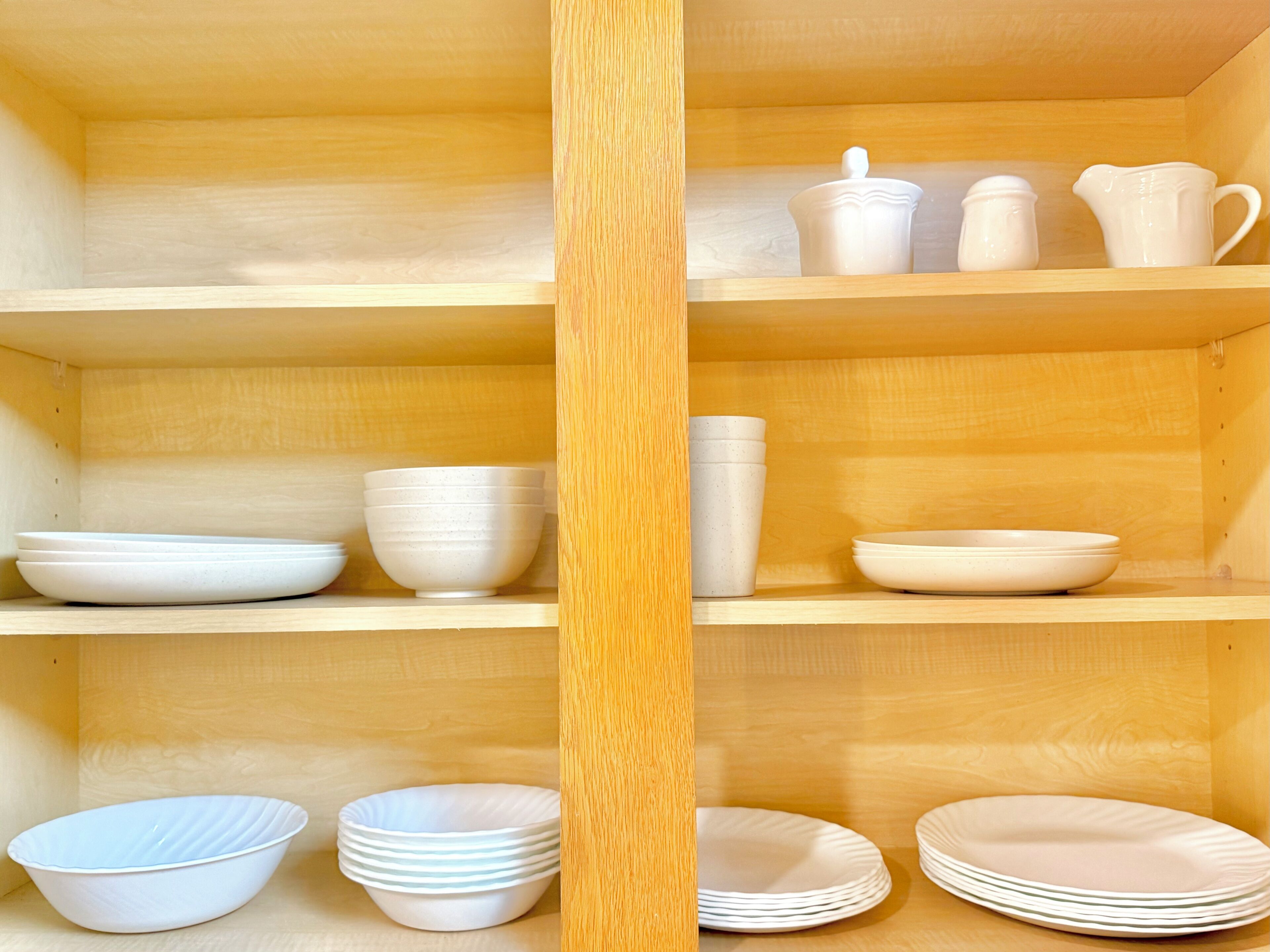 A wooden shelf with white ceramic dishes and bowls.