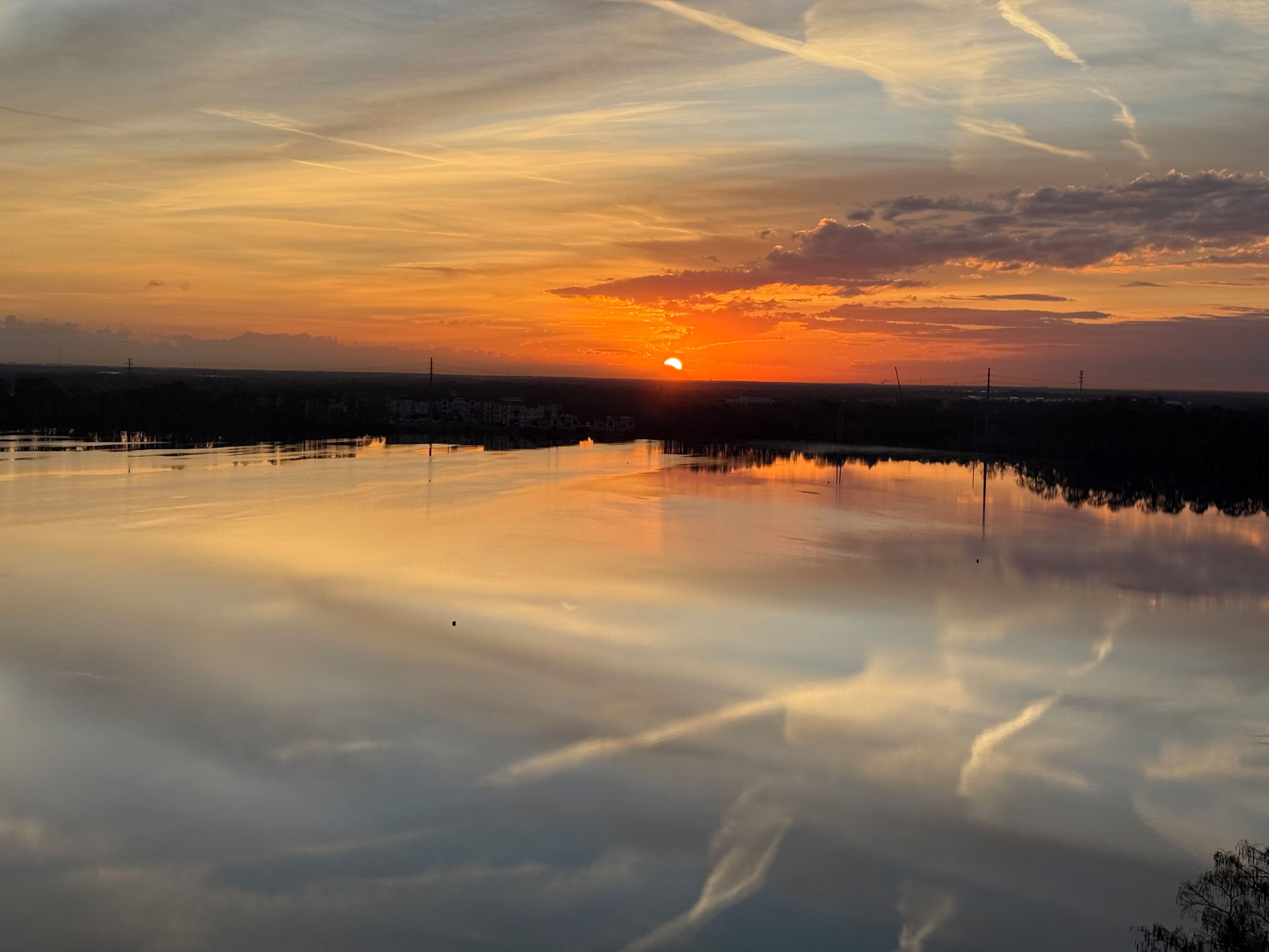 Ein Sonnenuntergang über ruhigem Wasser, der Horizont ist in der Ferne sichtbar.