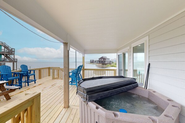 Relax on the deck with a hot tub and seating area overlooking a scenic view.
